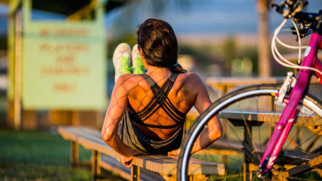 A woman doing a core exercise on a park bench in evening sun